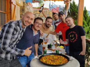 un grupo de hombres parados alrededor de una mesa con una pizza en Casa Mistral - Casa Rural Los Cuatro Vientos, en Moratalla