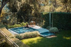 a woman sitting in a pool in a backyard at Hotel****Spa & Restaurant Cantemerle in Vence