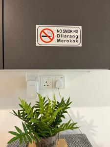 a no smoking sign on a wall with a plant at PadiViu Family Suite at Imperio Professional Suite, Alor Setar in Alor Setar