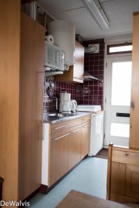 una cocina con armarios marrones y un aparato blanco en Appartement Walvis nr. 16B, en Vrouwenpolder 9 fotos más