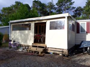 een kleine witte trailer met een bankje ervoor bij Bungalow de 3 chambres avec piscine partagee et jardin amenage a Saint Julien en Born a 5 km de la plage in Saint-Julien-en-Born