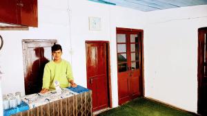 a man standing at a table in a room at The HappyTel in Mussoorie