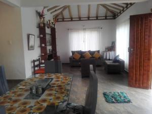 sala de estar con mesa de cristal y sofá en Tres habitaciones en la cabaña Quinta Buenos Aires, en Villa de Leyva