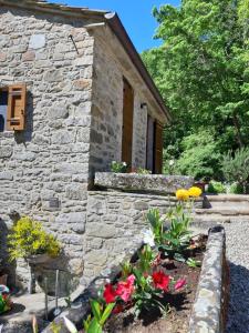 a stone house with flowers in front of it at Casetta nel bosco - L'Antico Metato in Pierle