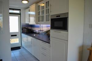 a kitchen with white cabinets and a sink at Appartement Walvis nr. 22B in Vrouwenpolder