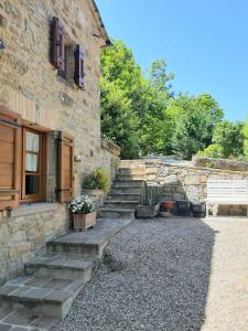 a stone house with stairs leading up to a building at Casetta nel bosco - L'Antico Metato in Pierle