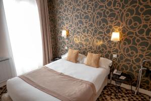 a bedroom with a bed and a wall with a wallpaper at Logis Hôtels Restaurant Les 3 Rois in Issoudun
