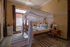 ein Schlafzimmer mit einem Himmelbett und einem Fenster in der Unterkunft Sunny Palms Beach Bungalows in Uroa