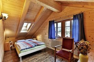 1 dormitorio en una cabaña de madera con 1 cama y 1 silla en BnB Chez Pia, en Ernen