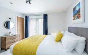 a bedroom with a large bed with a yellow blanket at High Range Holiday Apartments in Aviemore