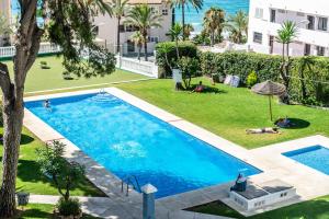 widok na basen z ludźmi leżącymi na trawie w obiekcie Cisnes Benalmádena Beach w mieście Benalmádena
