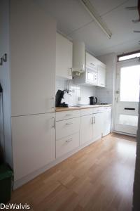 een keuken met witte kasten en een houten vloer bij Appartement Walvis nr. 9H in Vrouwenpolder