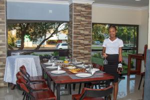 een vrouw die voor een tafel staat met eten bij Elephant View Lodge & Apartments in Livingstone