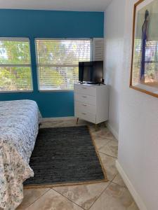 a bedroom with a bed and a tv and two windows at The Inn at Turtle Beach (Adults Only) in Siesta Key