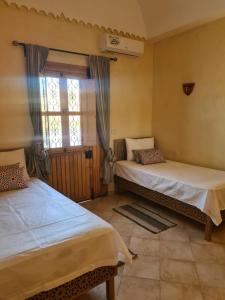 1 dormitorio con 2 camas y ventana en Villa Louiza, en Mezraya