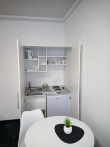 a small white kitchen with a white table with a plant on it at Hotel zur Kulturweberei in Finsterwalde