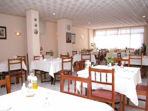 a dining room with white tables and wooden chairs at Hotel Bonaire in Revolta