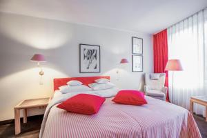 a bedroom with a large bed with red pillows at Romantik Hotel Landschloss Fasanerie in Zweibrücken