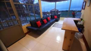 a living room with a black couch and red pillows at Hospedaje Villa Isabel in Aquitania