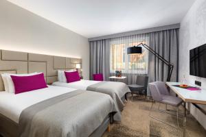 a hotel room with two beds and a desk at Mercure Krakow Stare Miasto in Kraków +132 photos