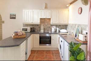 a kitchen with white cabinets and a counter top at Spacious Swallow Cottage in Tisbury