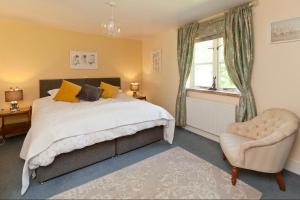 um quarto com uma cama, uma cadeira e uma janela em Spacious Swallow Cottage em Tisbury