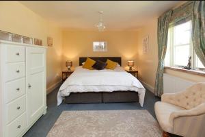 a bedroom with a bed and a couch and a chair at Spacious Swallow Cottage in Tisbury