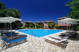 una piscina con due sedie a sdraio e ombrelloni di Saint Thomas Village a Città di Lefkada