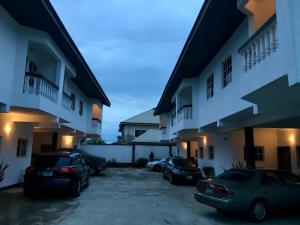 two cars parked in a parking lot in front of a building at Amoni Apartments in Port Harcourt