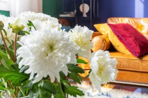 eine Vase mit weißen Blumen auf einem Tisch mit einer Couch in der Unterkunft Furnished Townhouse Ideally Located With 4 Bedrooms Large Terrace & Garden in Le Bouscat