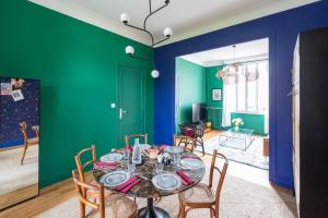 una sala da pranzo con pareti verdi e tavolo con sedie di Furnished Townhouse Ideally Located With 4 Bedrooms Large Terrace & Garden a Le Bouscat