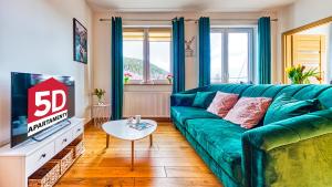 a living room with a green couch and a tv at Apartament Cichy - 5D Apartamenty in Świeradów-Zdrój