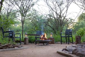a fire pit with chairs and a table and a table and chairs at Wildheart Safari - Zesty Zebra in Hoedspruit