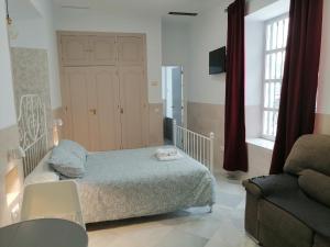 a bedroom with a bed and a chair and a couch at SALOTUR Tomas de Ibarra in Seville