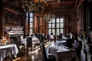 um restaurante com mesas e cadeiras e um piano em Rhinefield House Hotel em Brockenhurst