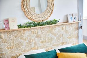 a mirror on a wall above a couch with pillows at Demeure de Manneville - SPA - 1Km des plages de Cabourg in Dives-sur-Mer
