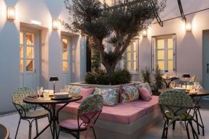 a patio with tables and chairs and a tree at Castro Hotel Syros in Ermoupoli