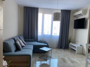 a living room with a blue couch and windows at Beach Residence Pomorie in Pomorie