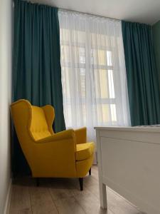 a yellow chair sitting in front of a window at Новый дом под Шпилем, центр in Barnaul