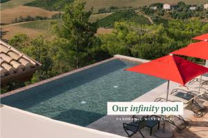a swimming pool with a red umbrella and chairs at Relais Cocci Grifoni - Panoramic Wine Resort in Offida