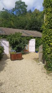 a yard with two white garage doors and a hedge at Logement entier dans village calme in Guillerval