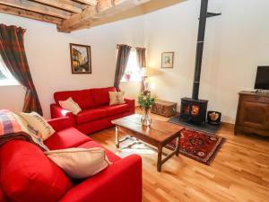 a living room with a red couch and a fireplace at Lower Barn in Hereford