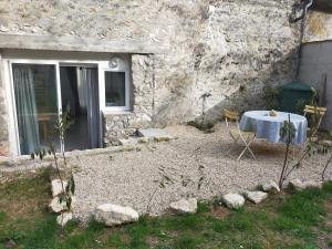 a table and chairs in front of a stone building at Logement entier dans village calme in Guillerval