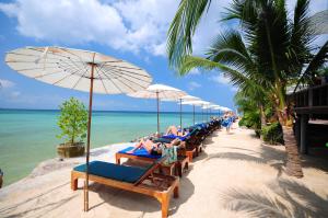 a row of beach chairs with umbrellas on a beach at Haad Yao Bayview Resort & Spa - SHA plus Certified in Haad Yao