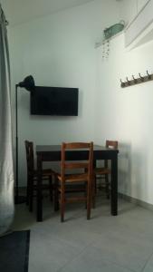 a dining room table with chairs and a television on a wall at Logement entier dans village calme in Guillerval