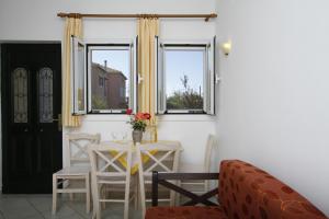 una sala da pranzo con tavolo, sedie e finestre di Saint Thomas Village a Città di Lefkada