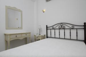 a bedroom with a bed and a desk and a mirror at Saint Thomas Village in Lefkada