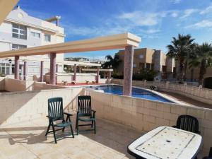 a patio with two chairs and a table and a pool at Mediterránea Solo Familias Serviplaya in Playa de Xeraco