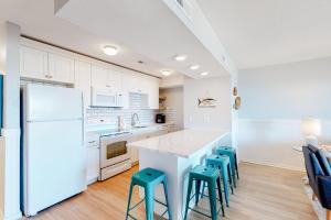 cocina con nevera blanca y taburetes en Surf & Sound, en Hatteras