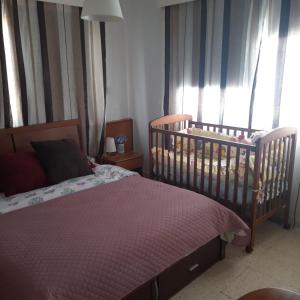 Schlafzimmer mit Kinderbett und Fenster mit Vorhängen in der Unterkunft La Veranda Sea View apartments in Larnaka